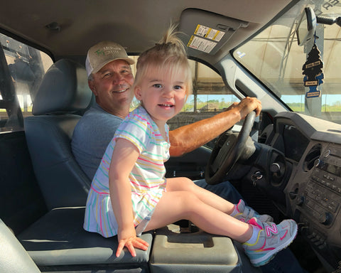 Man and child in a car, with the child sitting on the driver's seat.