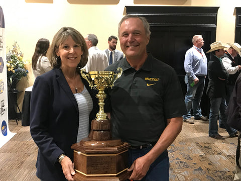 Woman and man standing together holding a trophy