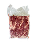 Packaged raw beef with marbling on a white background