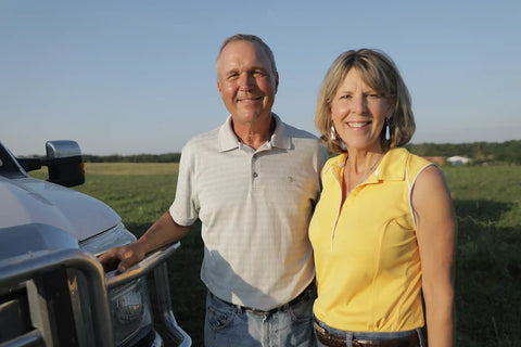 Man and woman standing next to a truck in a field