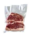 Two pieces of raw steak in a vacuum-sealed package on a white background