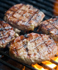 Three hamburgers cooking on a grill with flames below