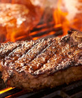 Steak being grilled over flames on a barbecue grill