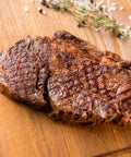 Grilled steak on a wooden cutting board with herbs