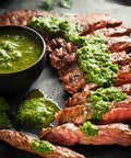 Grilled meat with green sauce on a dark surface