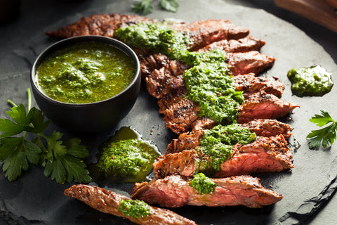Grilled meat with green sauce on a dark surface