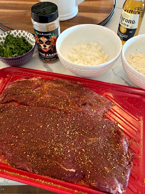 Marinated meat on a pink cutting board with seasonings and ingredients in the background.