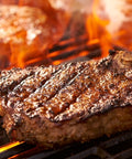 Steak being grilled with flames and smoke