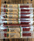 Multiple packages of beef sticks with a mixture of different flavors like Original, Teriyaki and Cheese and Peppers on a wooden surface