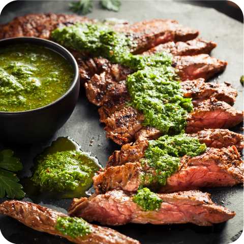 Sliced steak with green sauce on a dark surface