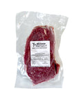 Raw beef flat iron steak in a clear plastic packaging with a label on a white background