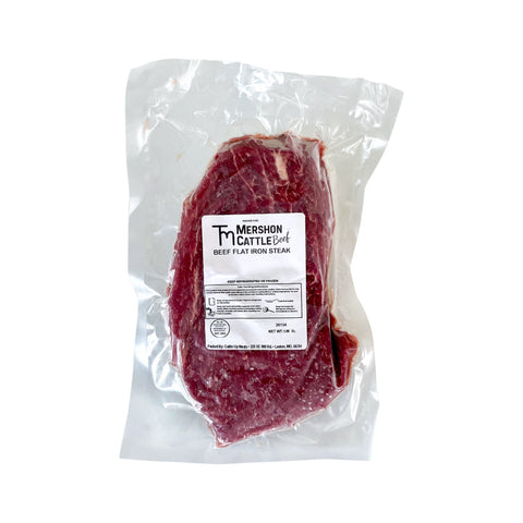 Raw beef flat iron steak in a clear plastic packaging with a label on a white background