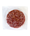 Round piece of raw meat in a clear plastic wrap on a white background