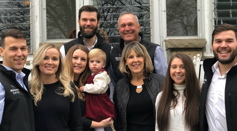 Family photo of a group of people standing outdoors in front of a house.