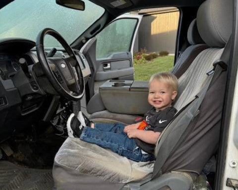 Child sitting in a car seat inside a vehicle with a scenic background