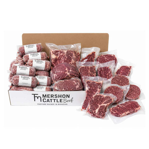 A Mershon Cattle Beef wholesale box filled with raw vacuum-sealed steaks, roasts, and ground meat, photographed on a white background.