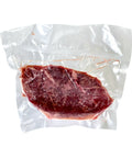 Vacuum-sealed raw steak on a white background
