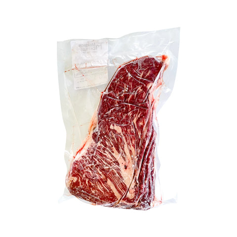 Vacuum-sealed raw steak in a clear plastic bag on a white background